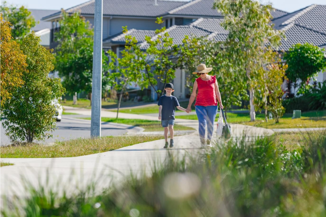 Woman and child walking on footpath with houses in background